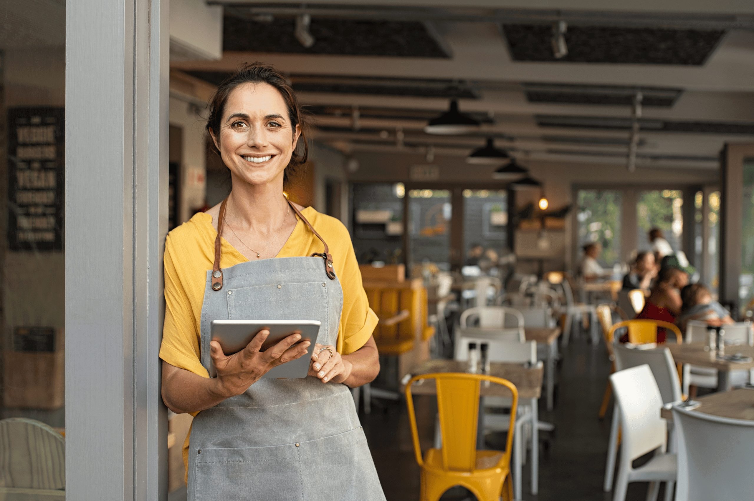 A small business woman standing in front of her store holding an iPad