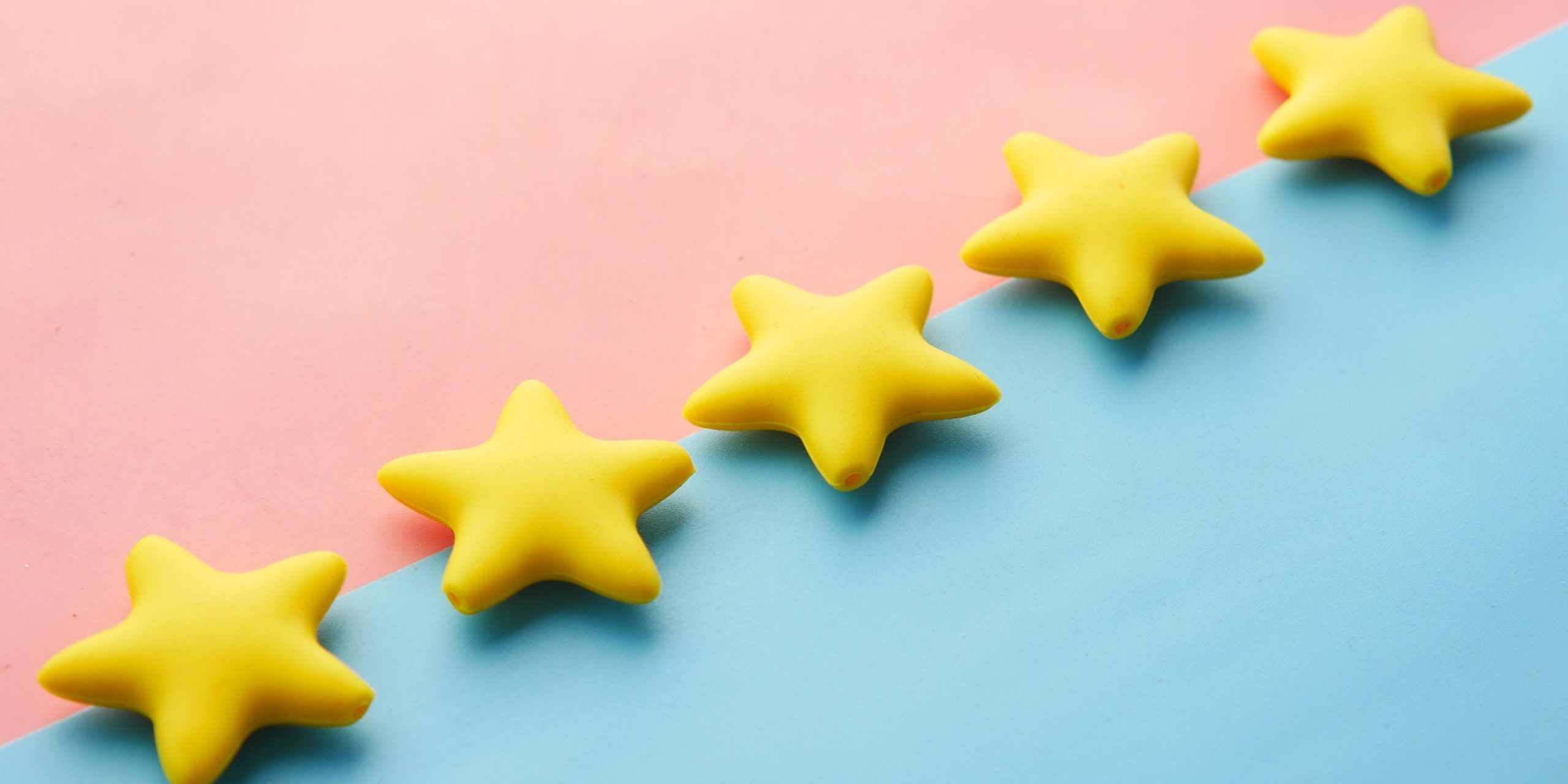 Five yellow stars lined diagonally on a pink and light blue background